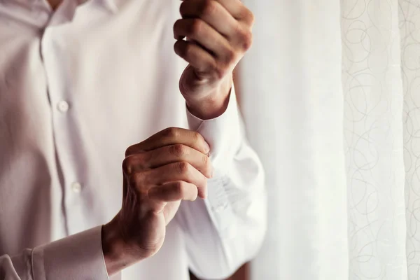 Businessman dress shirt. The man in the white shirt in the window dress cufflinks. Politician, man\'s style, Businessman buttoning his shirt,male hands closeup, American, European businessman