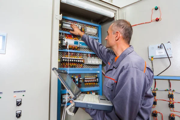 Electrician testing industrial machine, electrician builder engineer screwing equipment in fuse box, Male Electrician,energy conservation, electrical work, repair of electricit