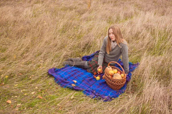 Young woman on the picnic with basket full of autumn harveat