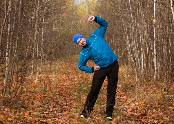 Man in a blue track suit in the autumn forest.