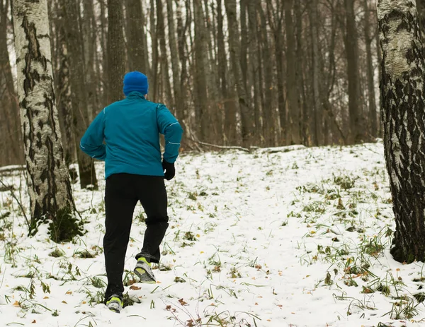 The man likes to run in the winter forest.