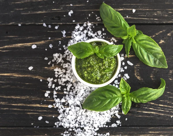 Pesto sauce in glass jar, sea salt and basil leaves