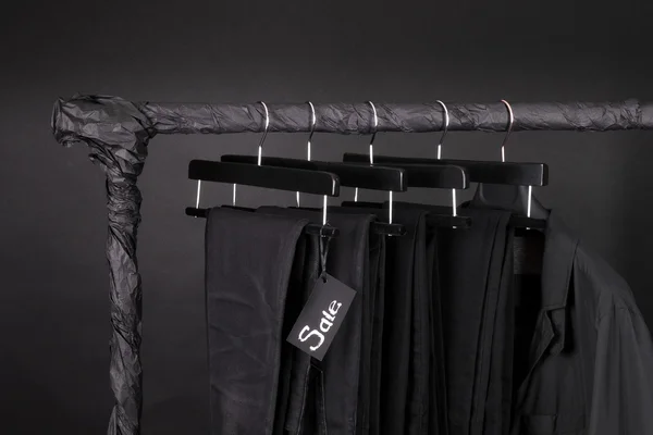 Lot of black pants jeans and jacket hanging on clothes rack.  background. sale sign.  friday. Close up.