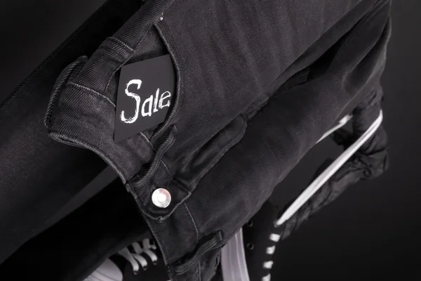 Close up of black jeans with sign Sale  hanging on clothes rack   background. Friday .