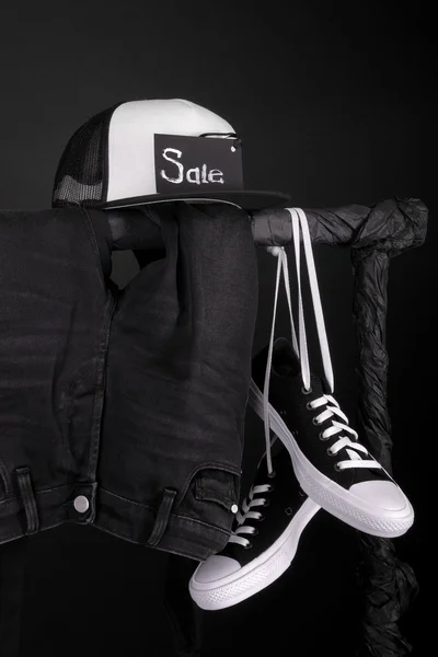 Sale sign. Black and white sneakers, cap  pant, jeans hanging on clothes rack   background.   friday. Close up.