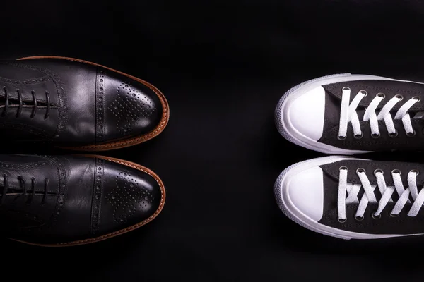 Mixed shoes. Oxford and sneakers shoe on black background.  Different style of men fashion. Compare  formal  casual. Top view. Copy space.