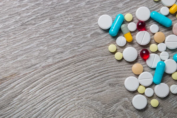Lot of colorful medication and pills from above on grey wooden background. Copy space. Top view, frame. Painkillers, tablets, generic , drugs.
