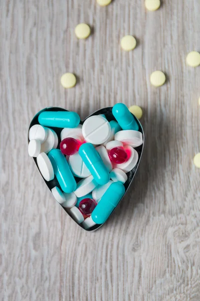 Heart from colorful medication and pills  above on grey wooden background. Copy space. Top view, frame. Painkillers, tablets, generic , drugs.