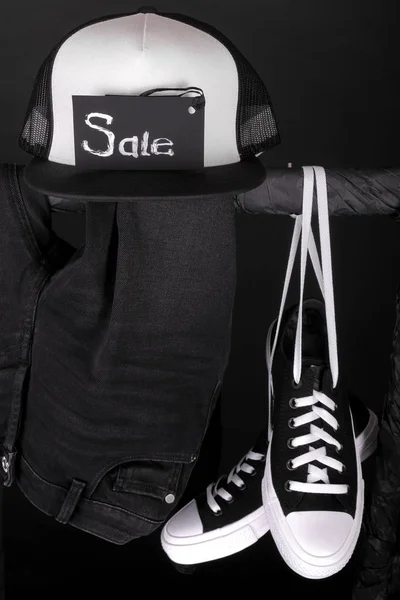 Sale sign. Black and white sneakers, cap  pant, jeans hanging on clothes rack   background.   friday. Close up.