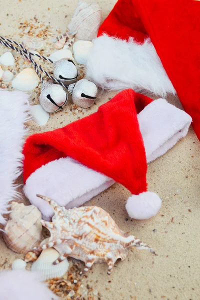 Three christmas hats on the beach. Santa hat  the sand near shells. Family holiday. New year vacation. Copy space. Frame. Top view.