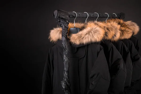 Black Friday. A lot of black coats, jacket with fur on hood hanging on clothes rack