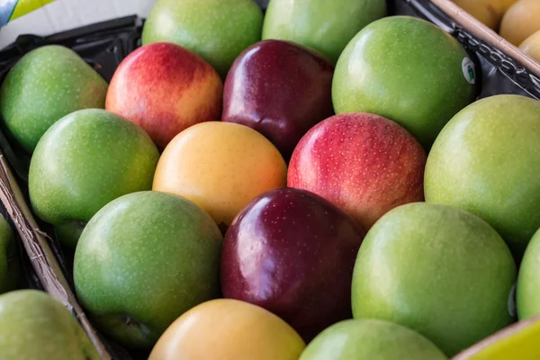 Four different types of ripe apples in a box.