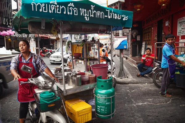 Asian woman driving a food cart, selling street food. Mobile Thai food vendor