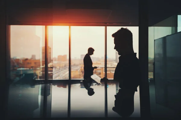 Silhouette of two businessmen in office interior