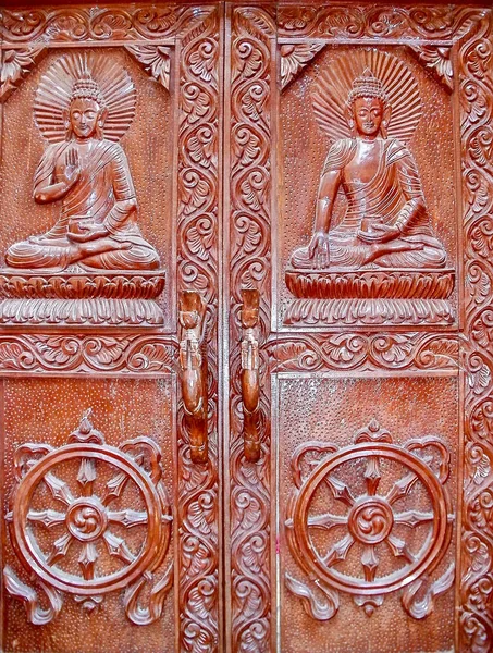 Wooden doors of the old Buddhist monastery of the 16th century with images of Buddha and the dharma wheel in Kathmandu, Nepal