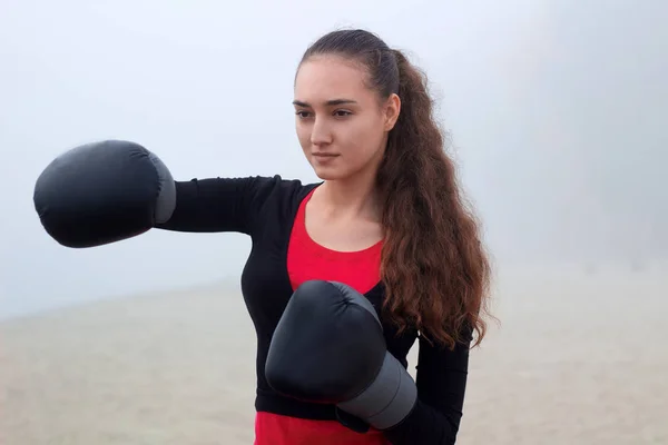 Young fitness girl does boxing exercises during training workout