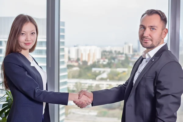 Young Asian business woman in suit shakes hands with his business partner