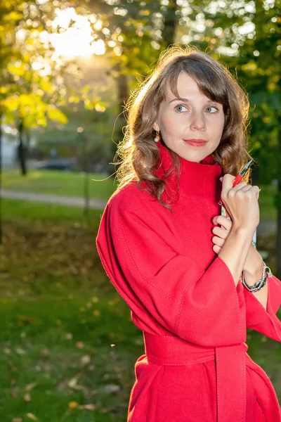 Beautiful woman in red coat posing in autumn Park