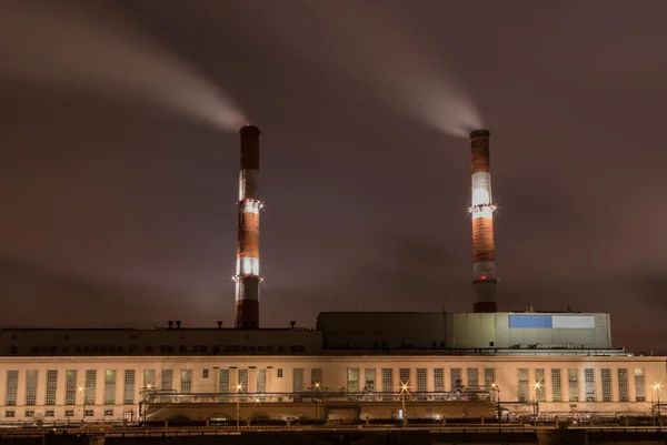 Factory with two smoke stack against sky at night