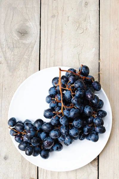 Bunch of ripe blue grapes on a light wooden background