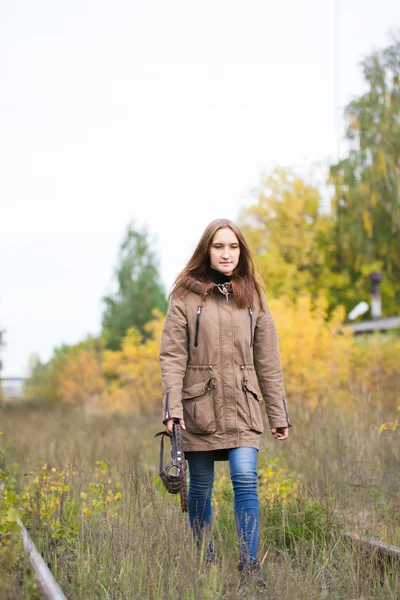 Portrait of young cute woman in fall autumn park. Beautiful caucasian girl walking in forest