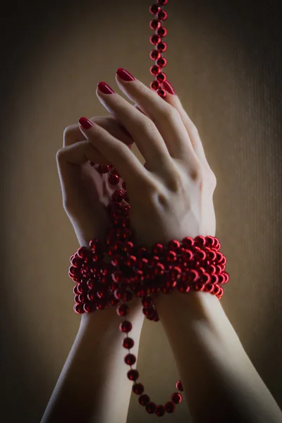Girl has hands bound with red beads - close up shot - illustrate pretty nail manicure