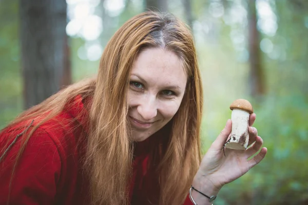 Young woman shows mushrooms boletus in the forest, close up