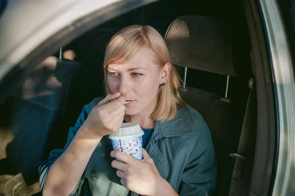 Girl eating ice cream with a spoon in the car