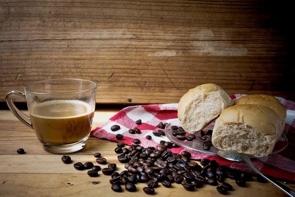 Hot coffee and bread on a wooden table. Dark background.