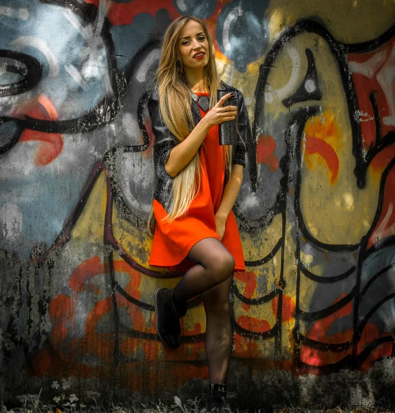 Beautiful girl with long hair in a red dress on  background of graffiti