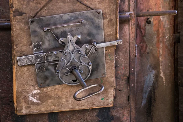 Old metal slip lock with key on a wooden substrate