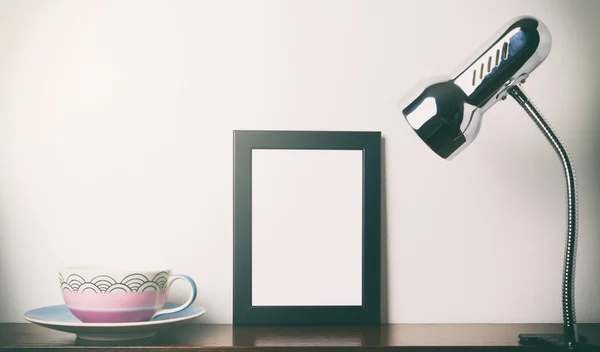 Tea cup and blank photo frame light up on a shelf