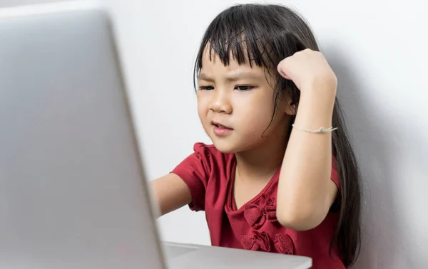 Japanese girl getting confuse on how to use the Internet. Asian kid is upset sitting in front of computer. A girl is confuse and think her home work is too hard.