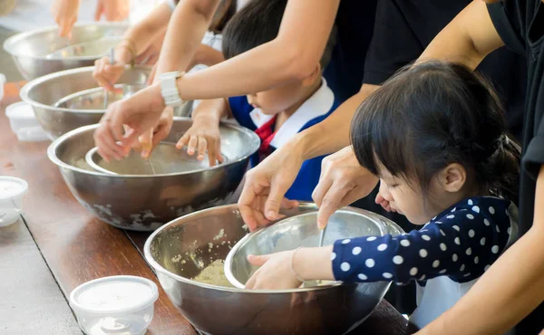 Asian kid and family is learning how to make ice cream in a cooking class.