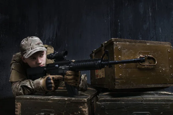 Coaching in-dash. Man in military uniform with assault rifle aiming at target on background of dark wall. Coaching in-dash.