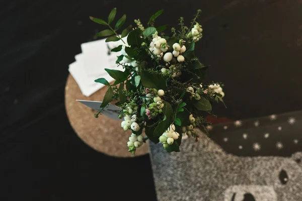 Small green bouquet with white berries on a black table top view