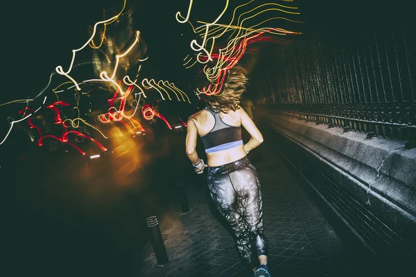 Woman practicing running in the city at night