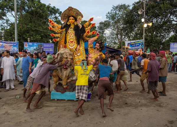 Puja workers push Durga idol to the Ganges river for immersion at Babughat Kolkata, West Bengal, India.