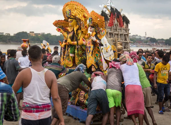 Durga puja workers push Durga idol to the Ganges river for immersion at Babughat Kolkata, West Bengal, India
