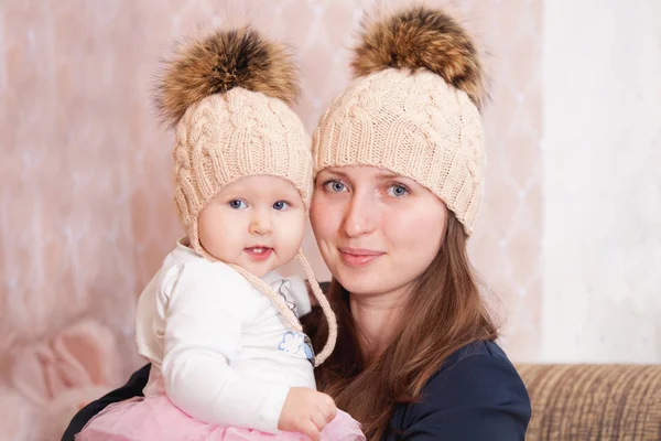 A young woman with her daughter in the same knitted caps