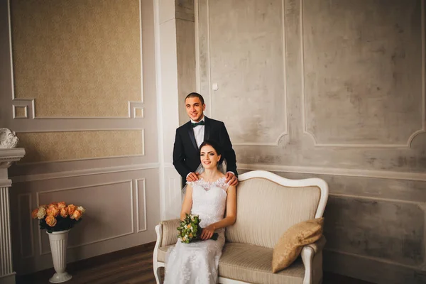 Happy sensual handsome groom and beautiful bride in white dress hugging close-up