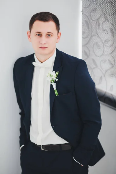 The groom in a suit in a rich hotel room