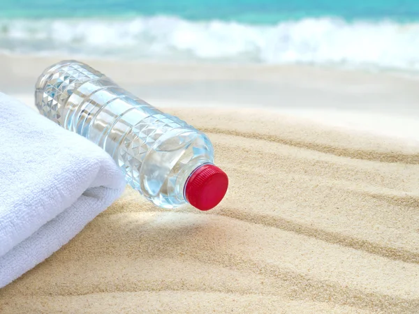 Mineral water bottle and towel on the beach