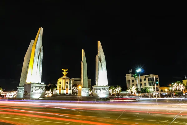 Night view of Democracy Monument in Bangkok, Thailand. The box in the middle represents the holding of Thai constitution and four wing like structures as four branches army forces guarding it.