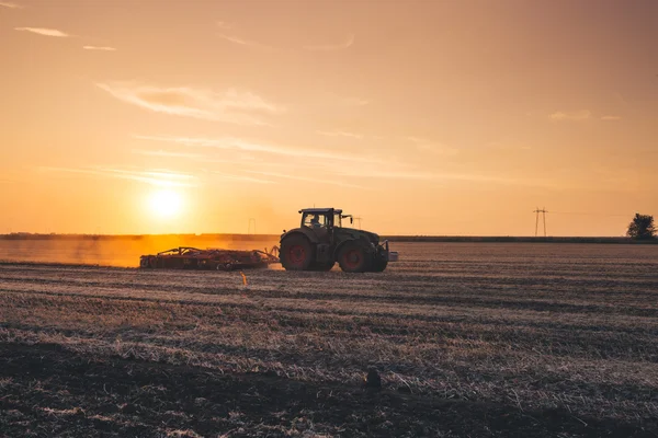 Tractor plowing during sunset