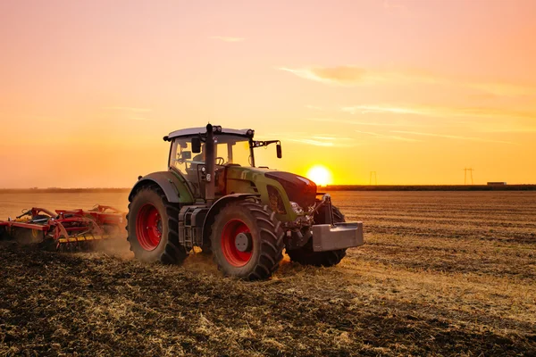 Tractor plowing during sunset