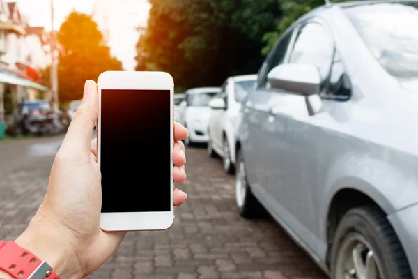 Man hand holding Smart phone showing blank screen with blur cars