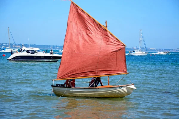 People sailing in a dinghy near the beach, Studland Bay.