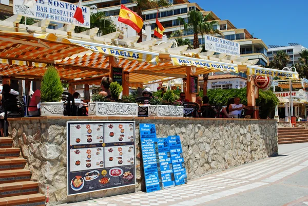 Tourists relaxing in pavement cafes on promenade, Benalmadena, Spain.