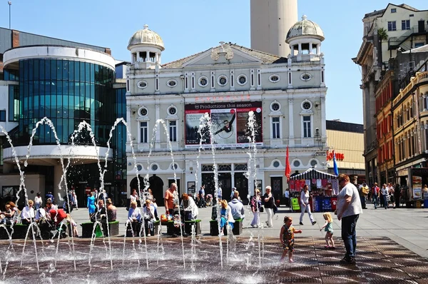 The Playhouse Theatre in Williamson Square with fountains in the foreground and people enjoying the Summer sunshine, Liverpool, UK.